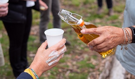 Person about to fill another person's cup with some lemon myrtle drink. Photo: Jessica Bray © DPIE