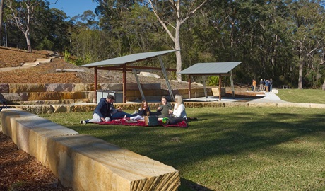A family shares a picnic lunch on the grass at Somersby Falls picnic area, Brisbane Water National Park. Credit: Stuart Cohen, Bottle Brush Media © DCCEEW