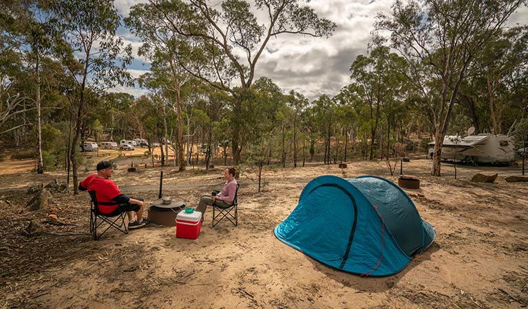 A man and woman sit around the fire ring beside their tent in Glendora campground at Hill End Historic Site. Photo: John Spencer/OEH